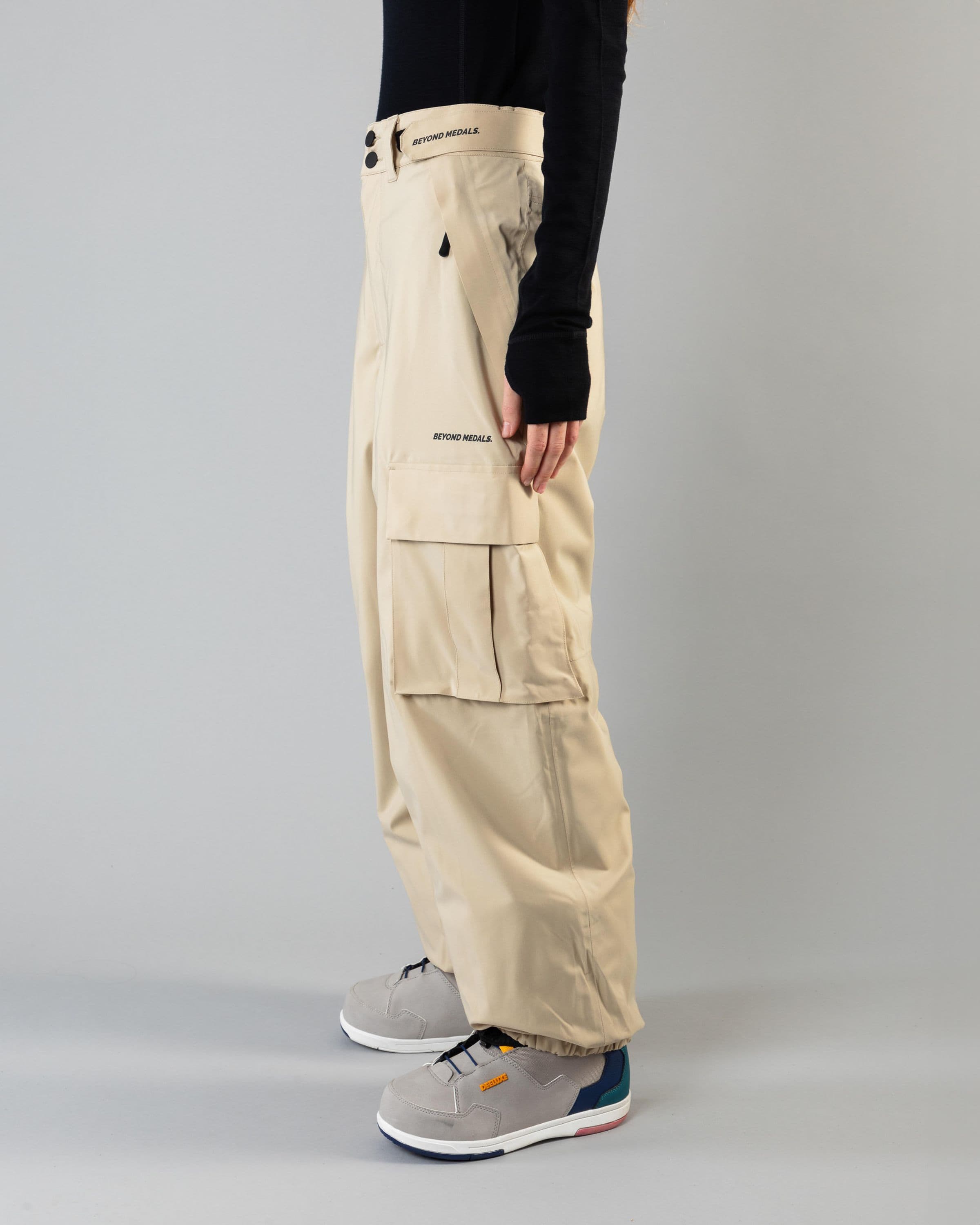Outerwear clothing, cargo pants in beige worn by model, Beyond Medals, 2024, side