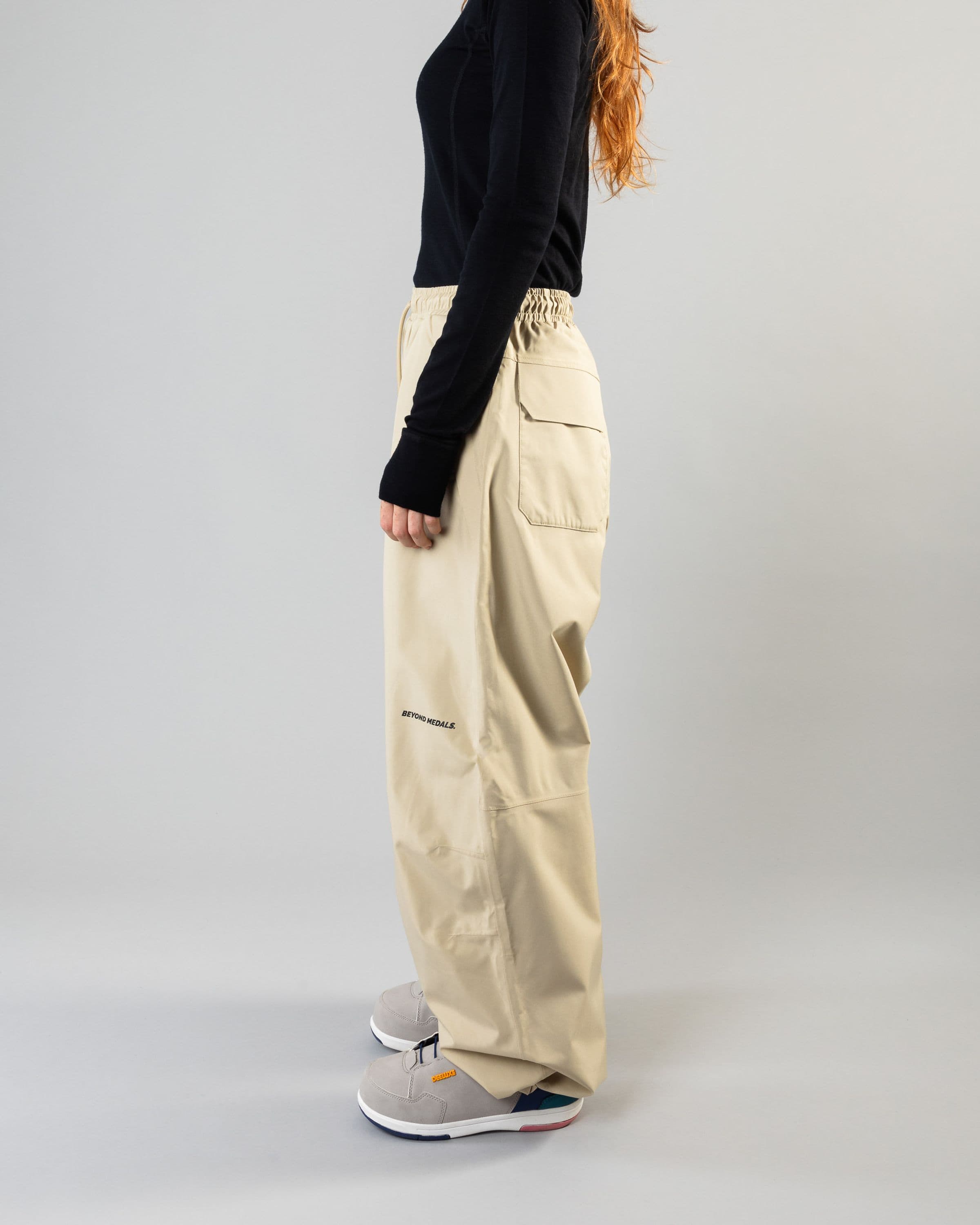 Outerwear clothing, park pants in beige worn by model, Beyond Medals, 2024, side