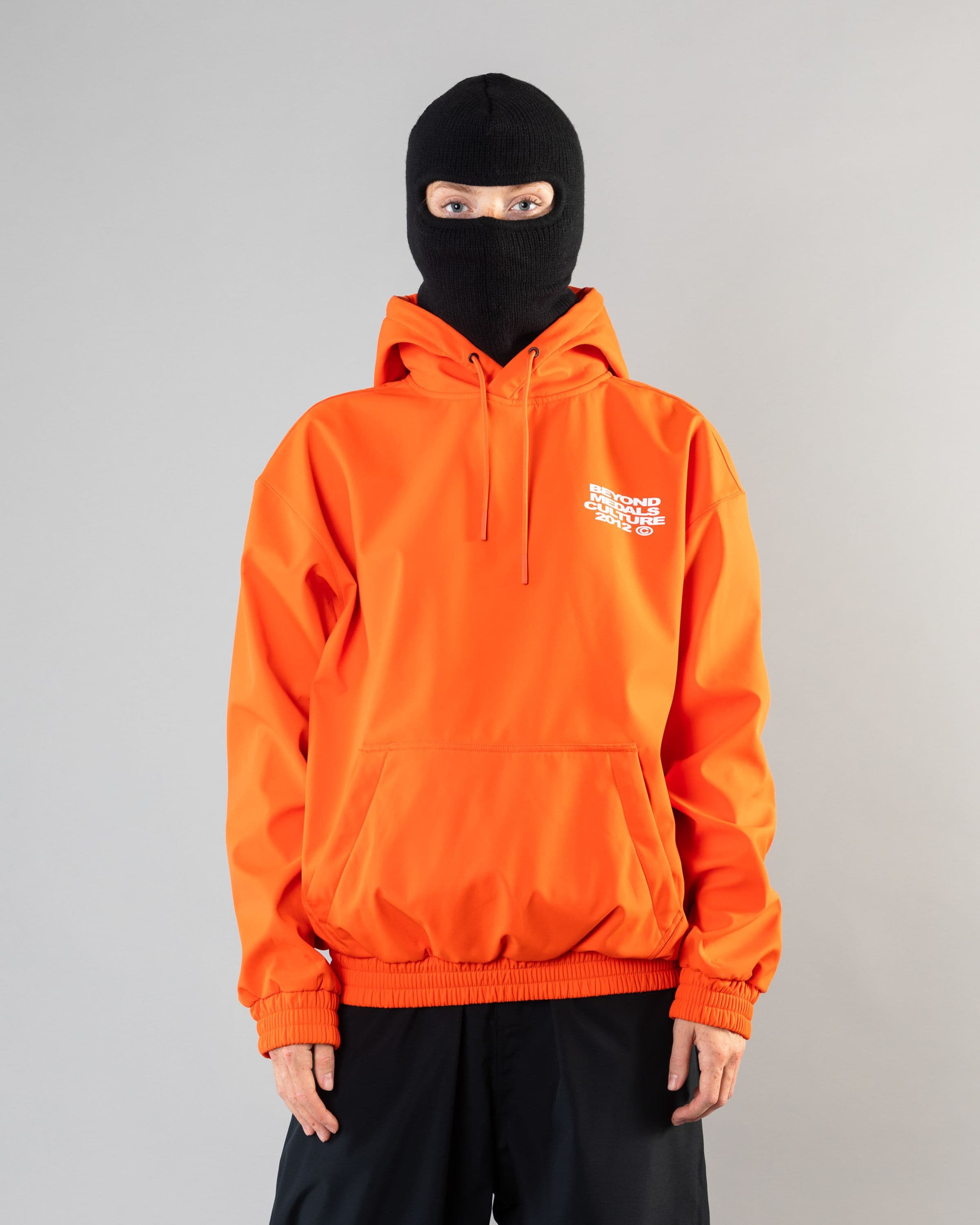 Outerwear clothing, softshell hoodie in orange worn by model, Beyond Medals, 2024, front