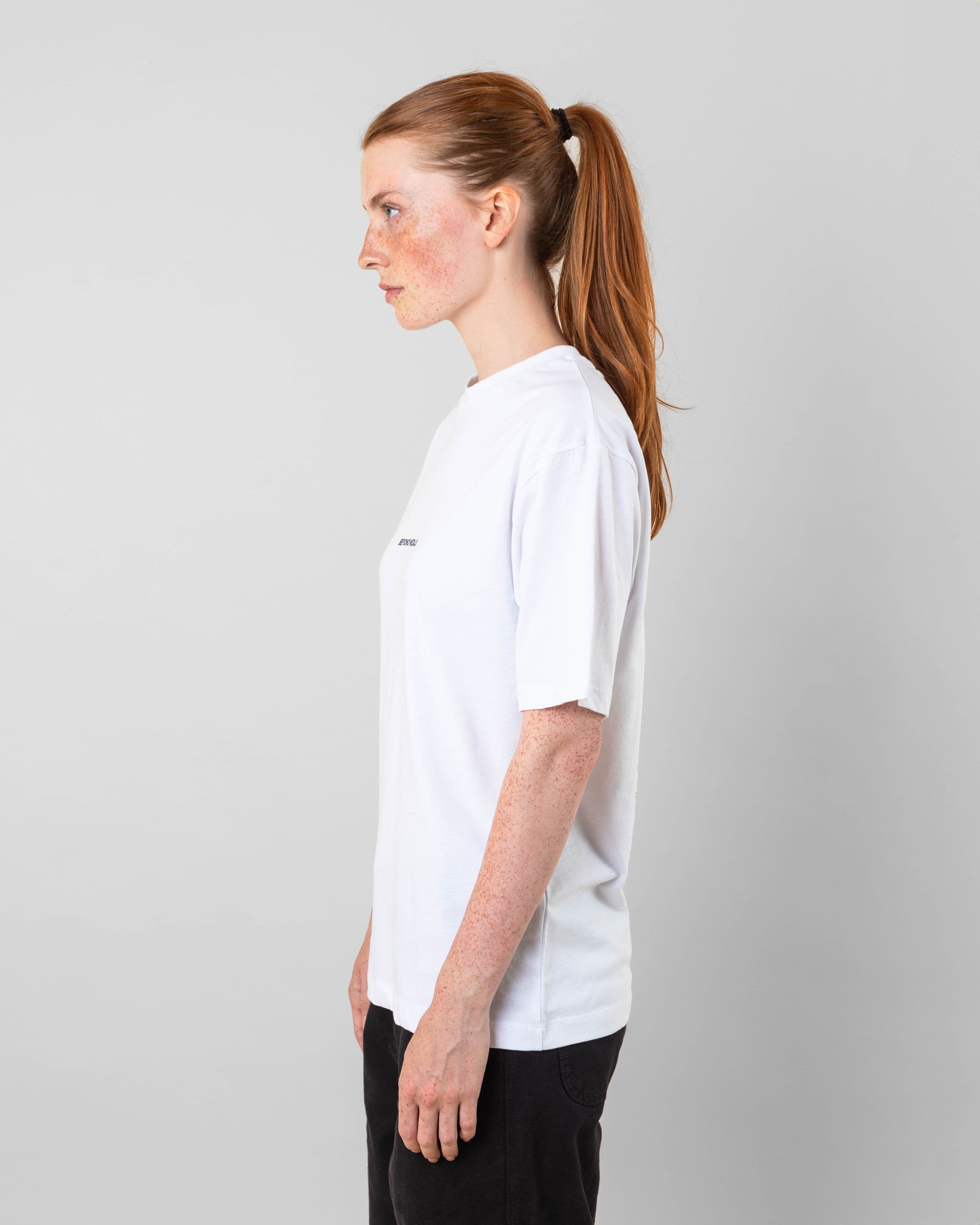 Streetwear clothing, baekkel tee in white worn by model, Beyond Medals, 2024 side