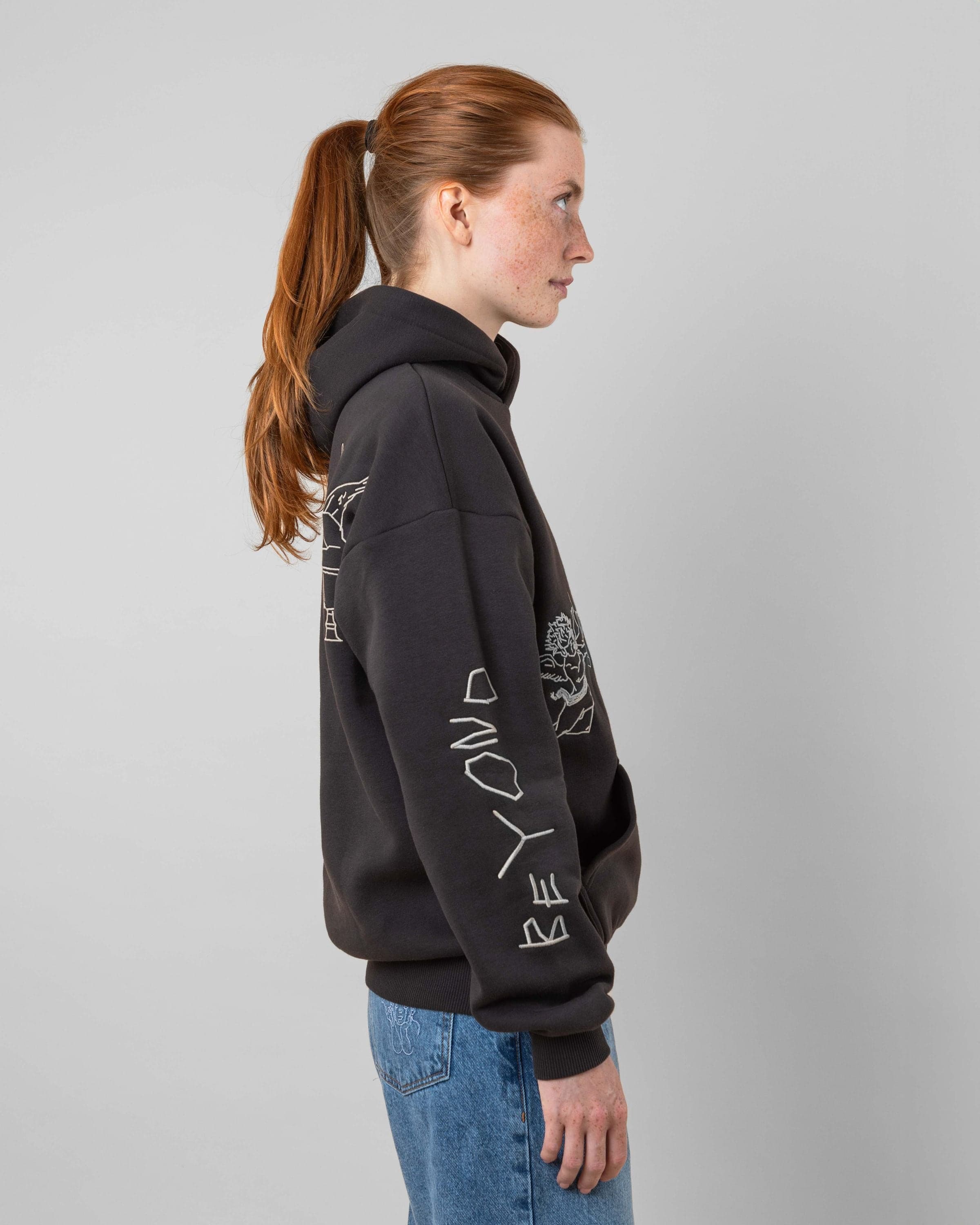 Streetwear clothing, angel hoodie 2.0 in grey worn by model, Beyond Medals, 2024, side1