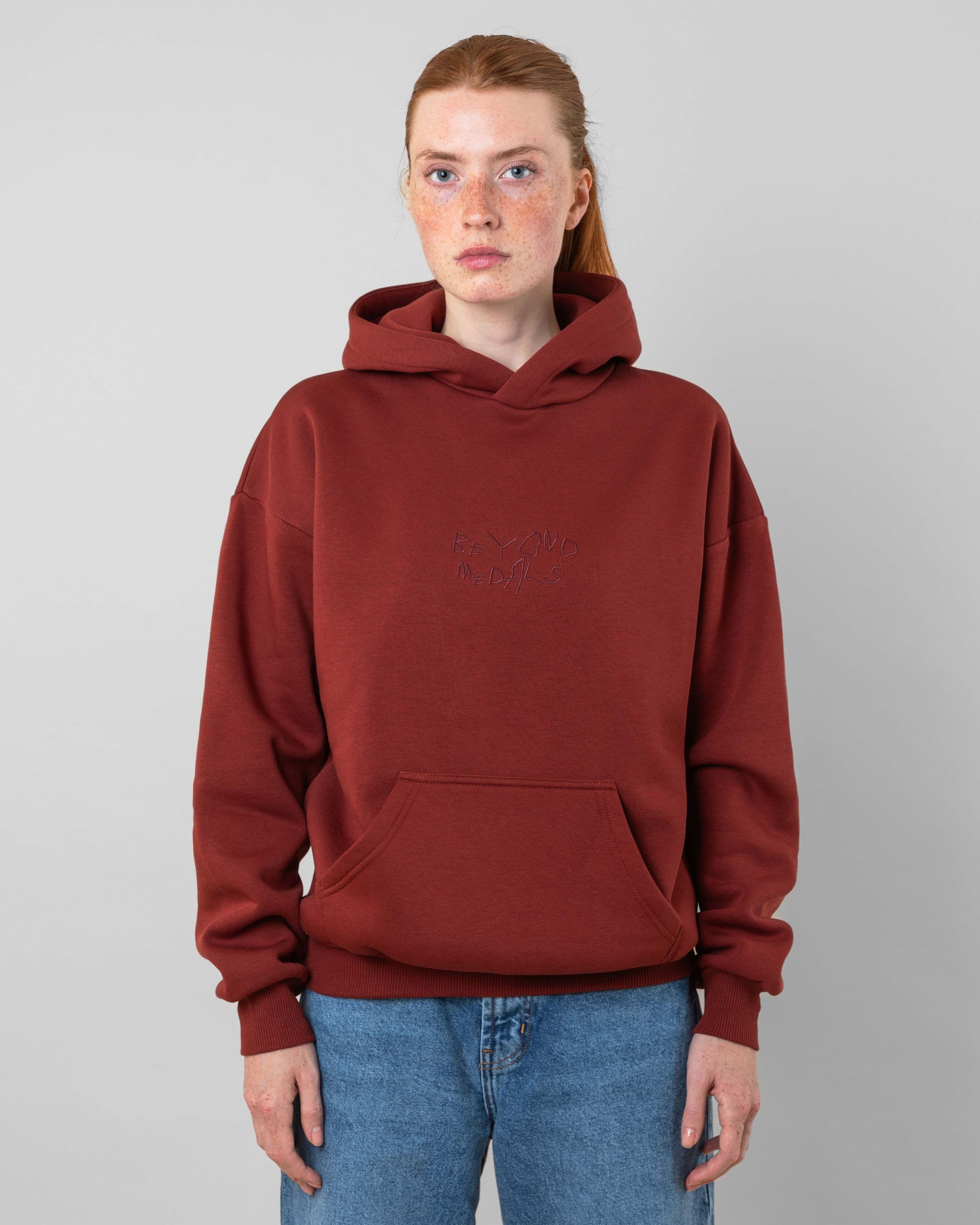 Streetwear clothing, angel hoodie 2.0 in red worn by model, Beyond Medals, 2024, front