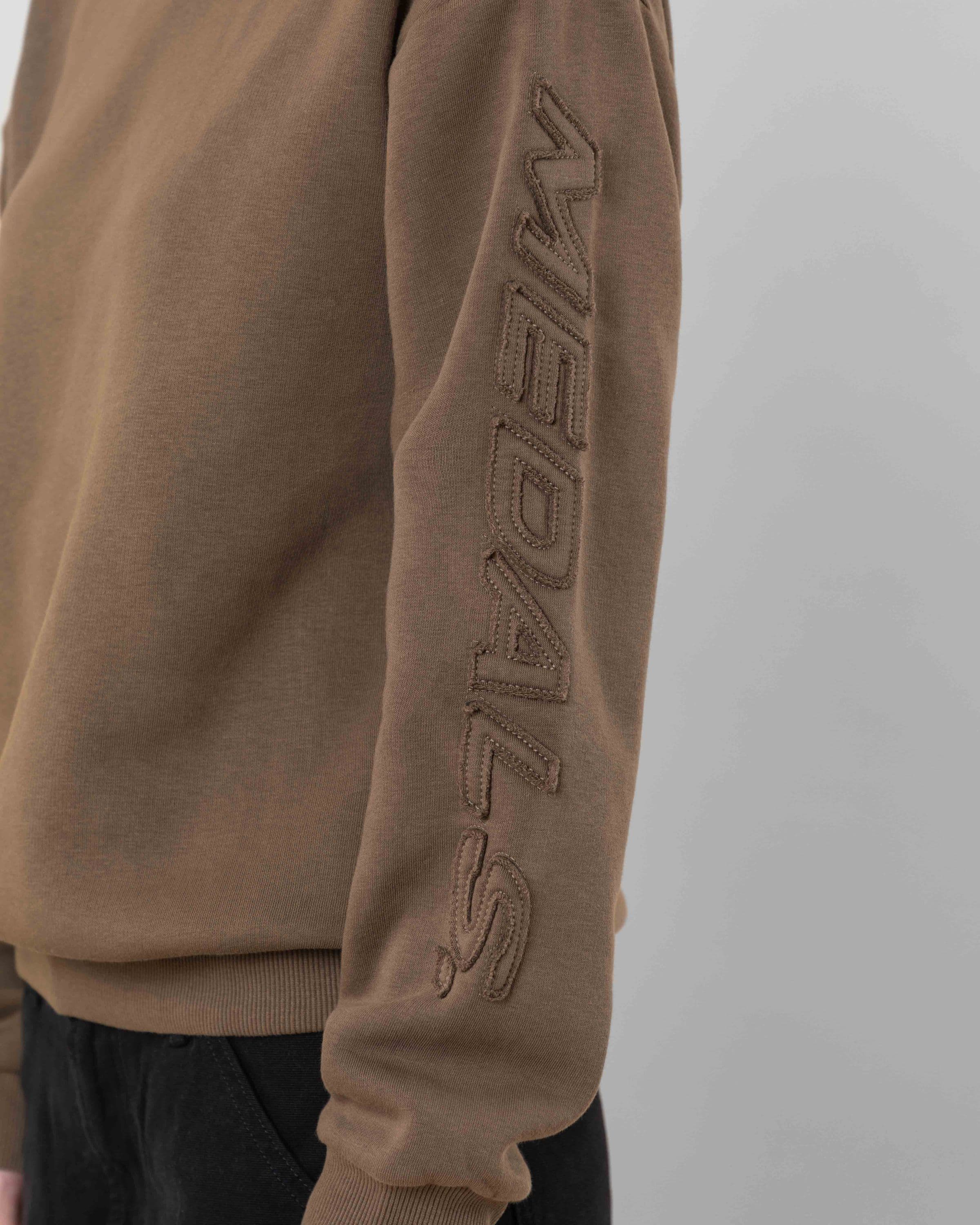 Streetwear clothing, incognito crewneck in brown worn by model, Beyond Medals, 2024, detail