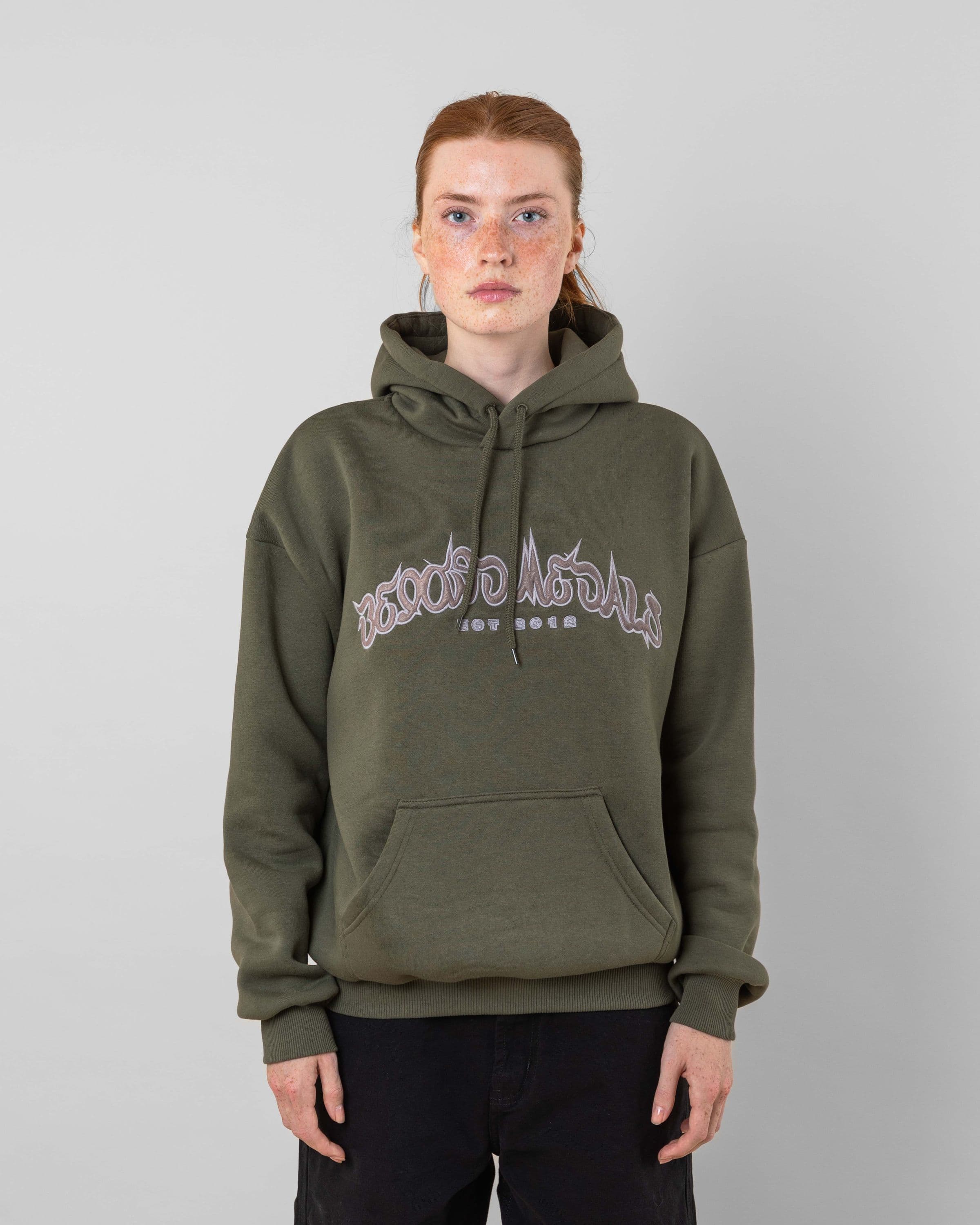 Streetwear clothing, 90s spike hoodie in green worn by model, Beyond Medals, 2024, front