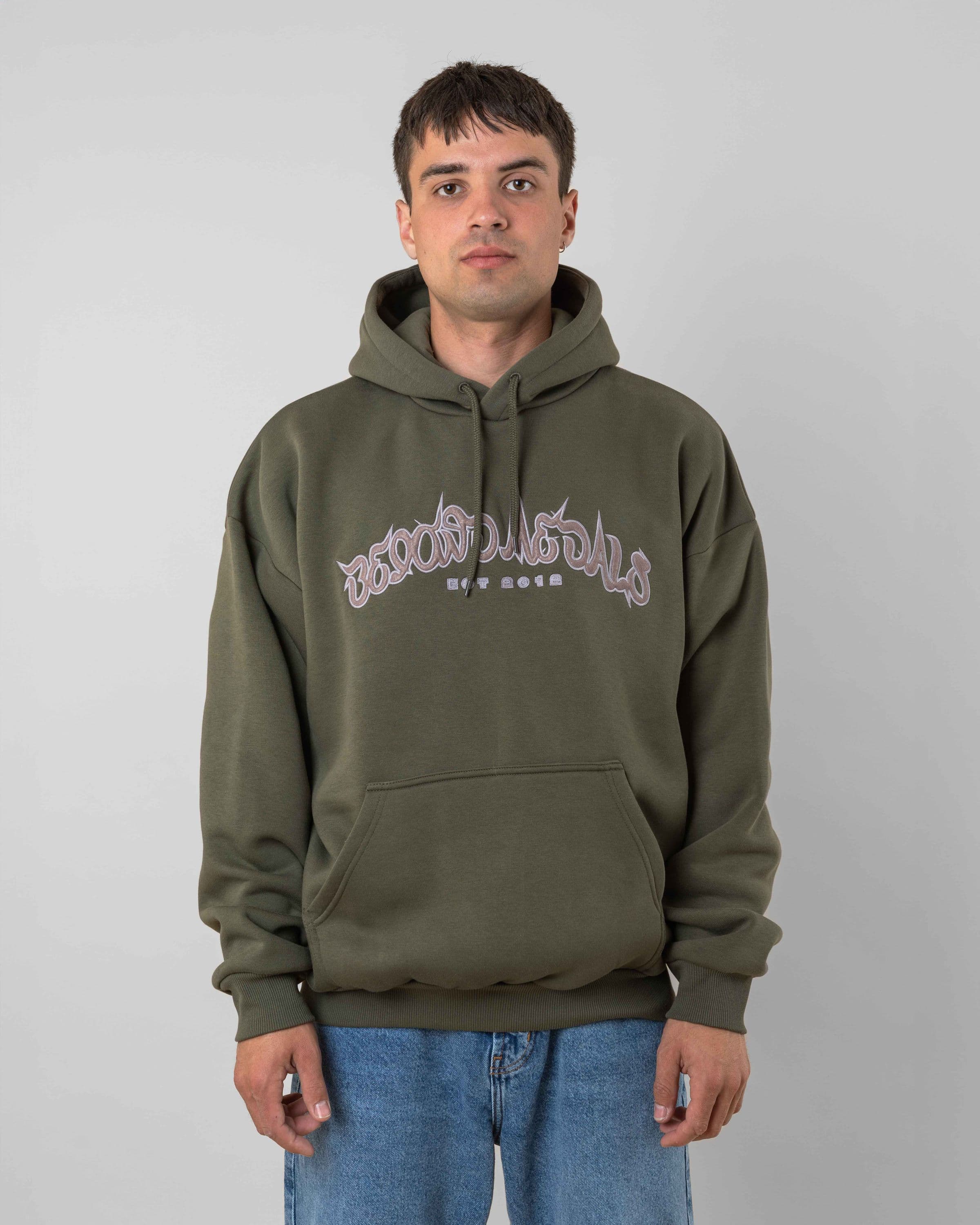 Streetwear clothing, 90s spike hoodie in green worn by model, Beyond Medals, 2024, front1