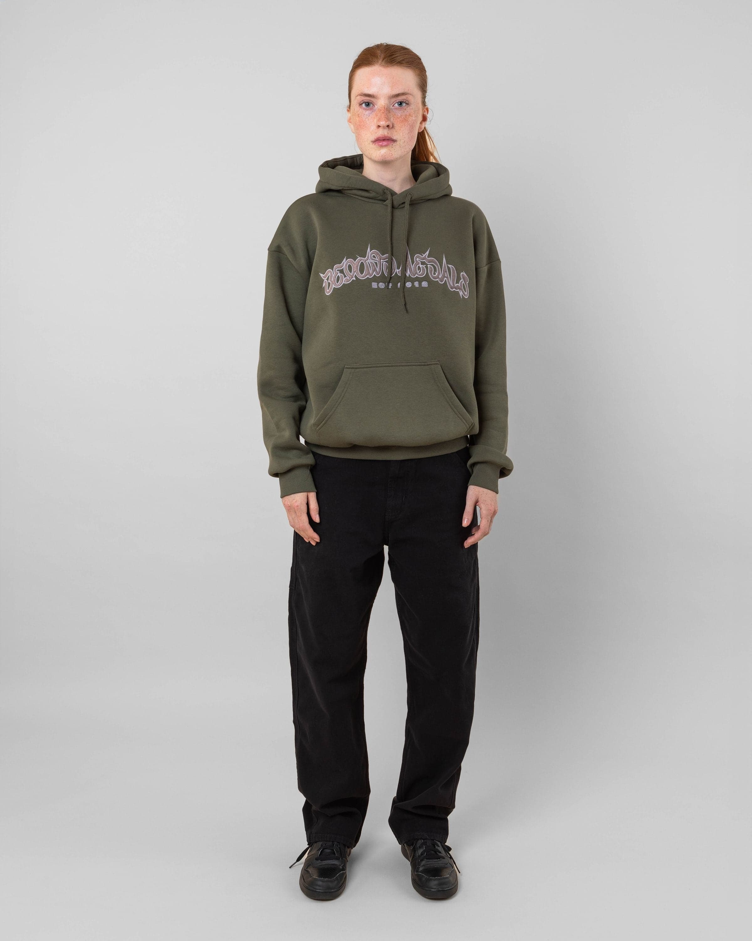 Streetwear clothing, 90s spike hoodie in green worn by model, Beyond Medals, 2024, full front