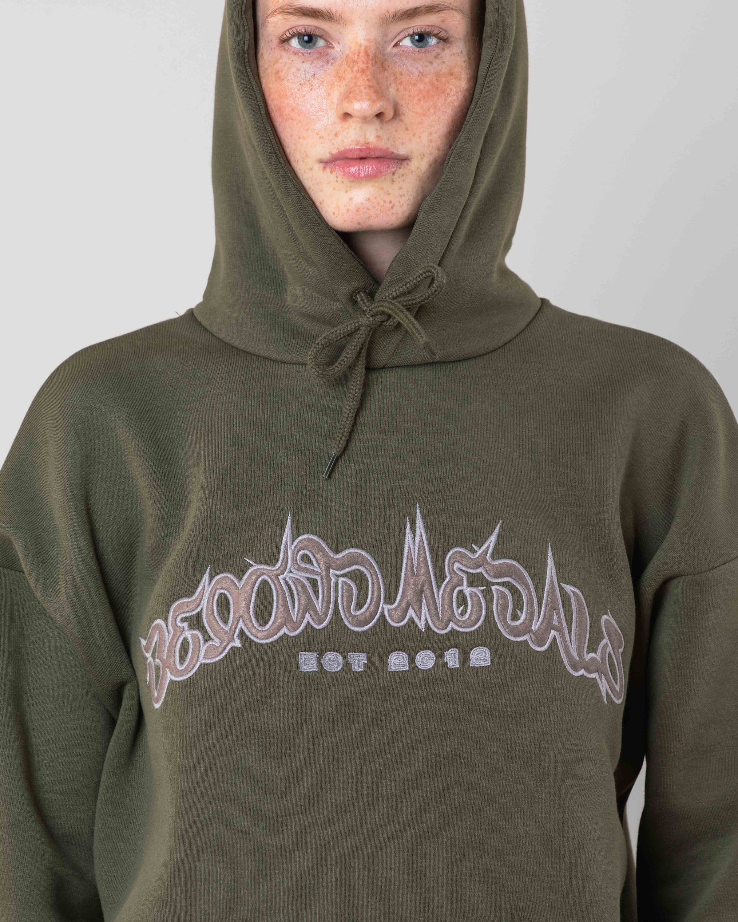 Streetwear clothing, 90s spike hoodie in green worn by model, Beyond Medals, 2024, detail